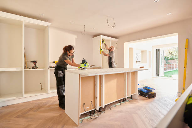 Два плотника устанавливают шкафы в проекте ремонта современной кухни.